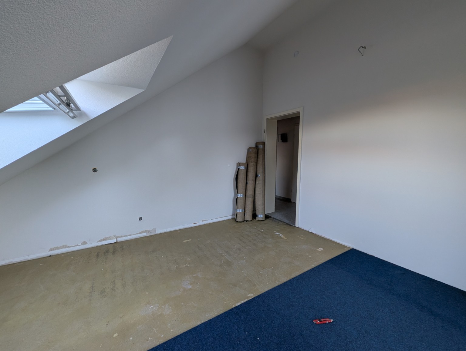 Dachzimmer vor den Arbeiten mit sichtbaren Schadstellen an der Wand, Blick zur Zimmertür